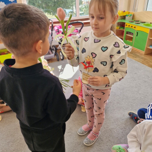 Chłopiec składa życzenia koleżance z grupy i wręcza tulipana z okazji Dnia Kobiet