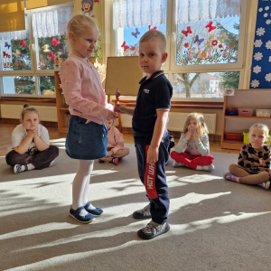 Chłopiec wręcza dziewczynce drewniany kwiatek z lizakiem z okazji Dnia Kobiet