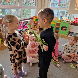 Chłopiec składa życzenia koleżance z grupy i wręcza tulipana z okazji Dnia Kobiet