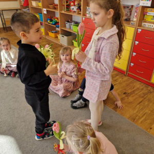 Chłopiec składa życzenia koleżance z grupy i wręcza tulipana z okazji Dnia Kobiet