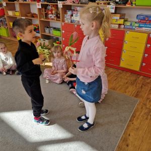 Chłopiec składa życzenia koleżance z grupy i wręcza tulipana z okazji Dnia Kobiet