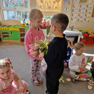 Chłopiec składa życzenia koleżance z grupy i wręcza tulipana z okazji Dnia Kobiet