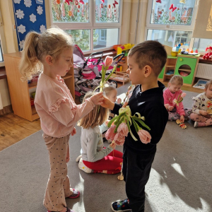 Chłopiec składa życzenia koleżance z grupy i wręcza tulipana z okazji Dnia Kobiet