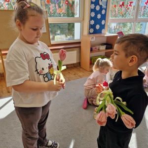 Chłopiec składa życzenia koleżance z grupy i wręcza tulipana z okazji Dnia Kobiet