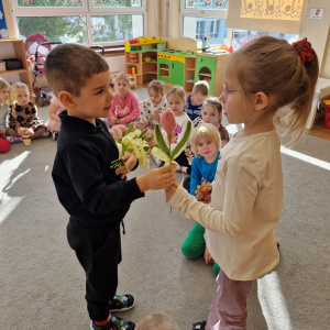 Chłopiec składa życzenia koleżance z grupy i wręcza tulipana z okazji Dnia Kobiet