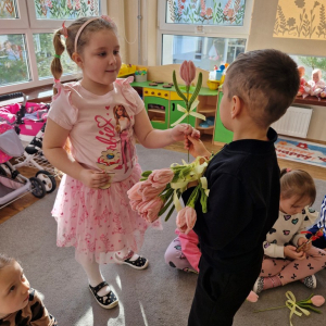 Chłopiec składa życzenia koleżance z grupy i wręcza tulipana z okazji Dnia Kobiet