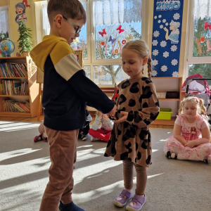 Chłopiec wręcza dziewczynce drewniany kwiatek z lizakiem z okazji Dnia Kobiet