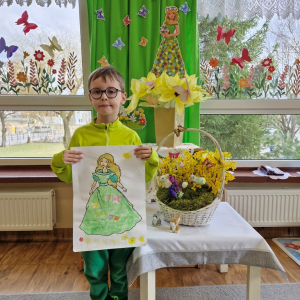 Chłopiec  prezentuje swoją pracę plastyczną "Pani Wiosna"