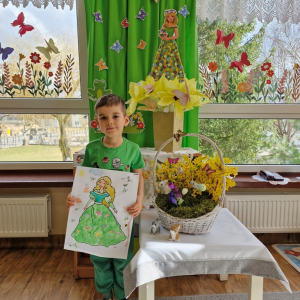 Chłopiec  prezentuje swoją pracę plastyczną "Pani Wiosna"