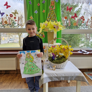 Chłopiec  prezentuje swoją pracę plastyczną "Pani Wiosna"