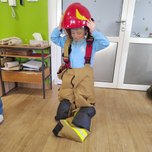 Dziecko przymierza strój strażaka.