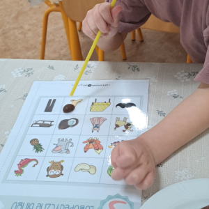 Dziewczynka przenosząca płatki przy użyciu słomki. 
