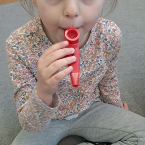 Dziewczynka grająca na Kazoo - doskonalenie świadomego używanie głosu i uruchamiania więzadeł głosowych.
