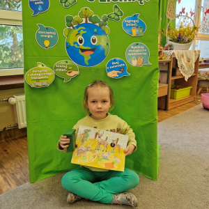 Dziewczynka prezentuje  pracę plastyczną "Wielkie porządki w lesie"