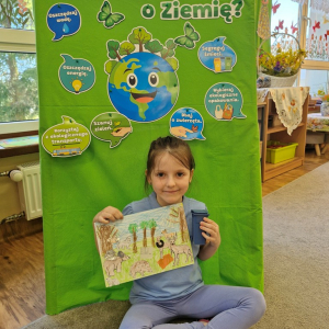 Dziewczynka prezentuje  pracę plastyczną "Wielkie porządki w lesie"