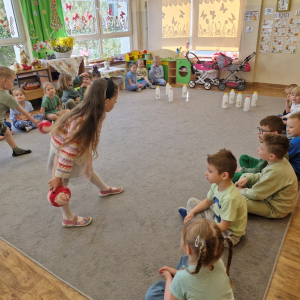 Dzieci rzucają kulą w czasie zabawy "Butelkowe kręgle"