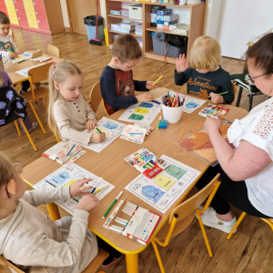 Dzieci w czasie pracy przy stoliku - wykonują zadanie w karcie pracy ( kolorują kosze i łączą obrazki przedstawiające odpady z  odpowiednimi pojemnikami) 