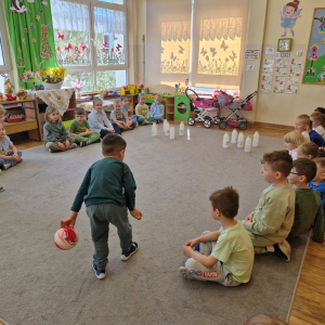 Dzieci rzucają kulą w czasie zabawy "Butelkowe kręgle"