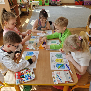 Dzieci w czasie pracy przy stoliku - wykonują zadanie w karcie pracy ( kolorują kosze i łączą obrazki przedstawiające odpady z  odpowiednimi pojemnikami) 