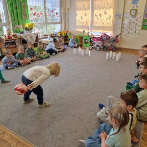 Dzieci rzucają kulą w czasie zabawy "Butelkowe kręgle"