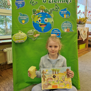 Dziewczynka prezentuje  pracę plastyczną "Wielkie porządki w lesie"