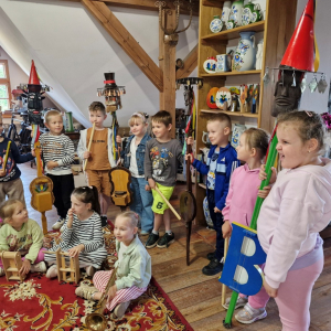 Dzieci trzymają kaszubskie ludowe instrumenty muzyczne, tworząc dziecięcą orkiestrę