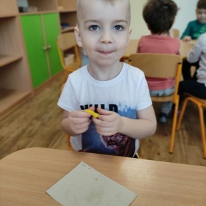 Chłopiec siedzący przy stoliku lepi owoce i warzywa z plasteliny