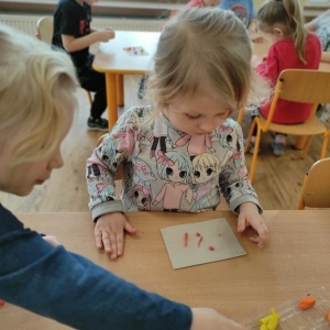 Dzieci siedzące przy stoliku lepią owoce i warzywa z plasteliny